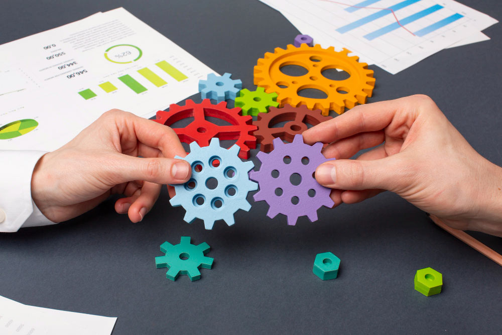 Manos uniendo engranajes de colores sobre documentos y gráficos