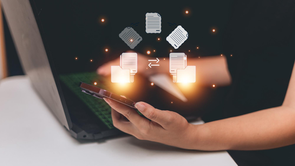 Usuario con móvil y portátil intercambiando archivos