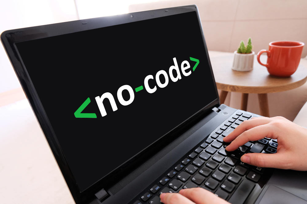 Laptop con la palabra "No-Code" en pantalla, representando desarrollo sin programación.