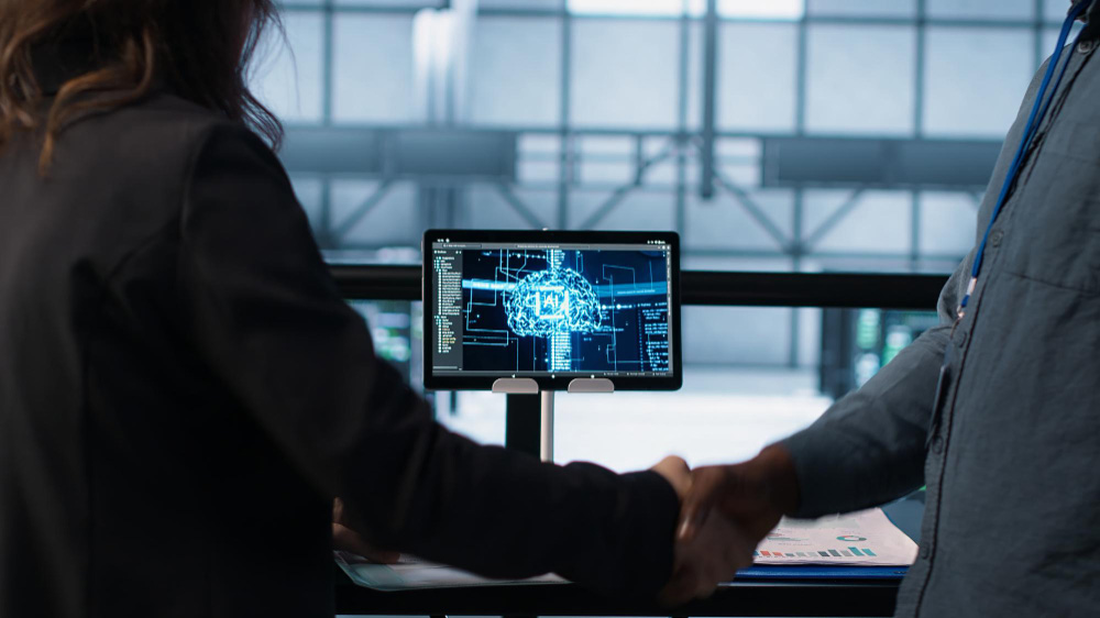Apretón de manos entre empresarios con una pantalla que muestra la inteligencia artificial en Colombia de fondo