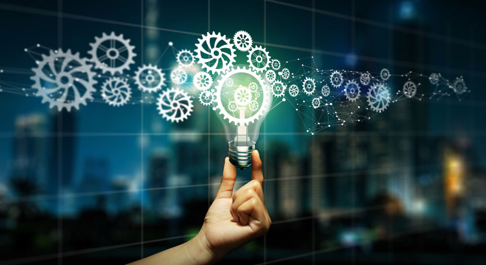 Mano sosteniendo una bombilla rodeada de engranajes y elementos digitales que representan innovación en procesos empresariales.